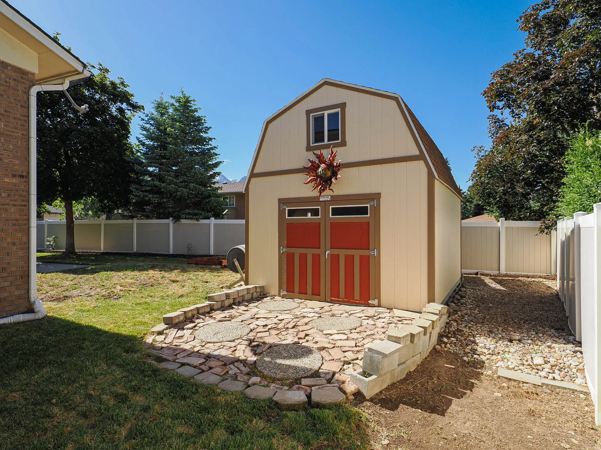 Detached barn-style shed featuring a gambrel roof and red double doors
