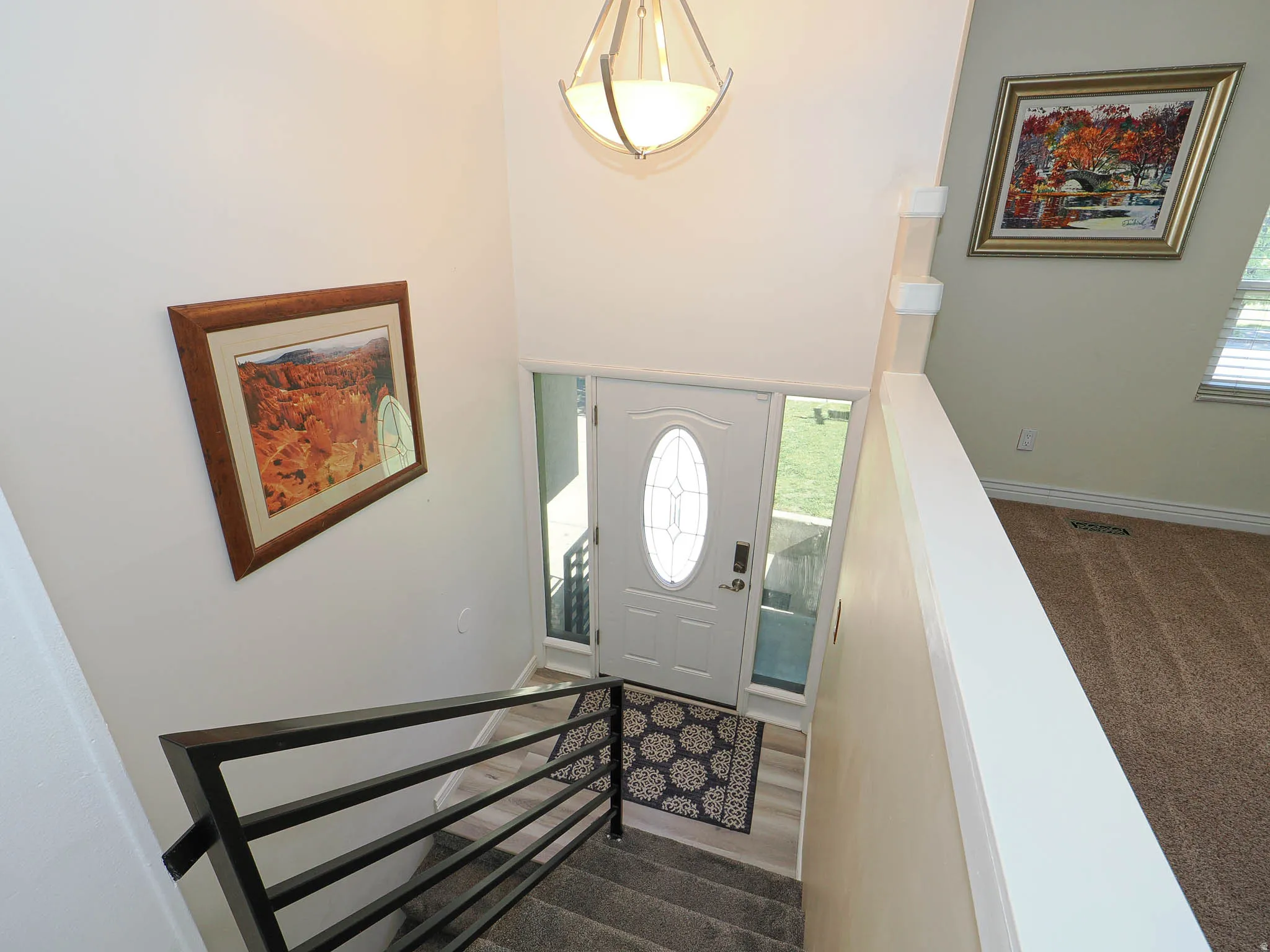 Entryway featuring a white door with an oval glass insert, side light panels, and a contemporary pendant light fixture