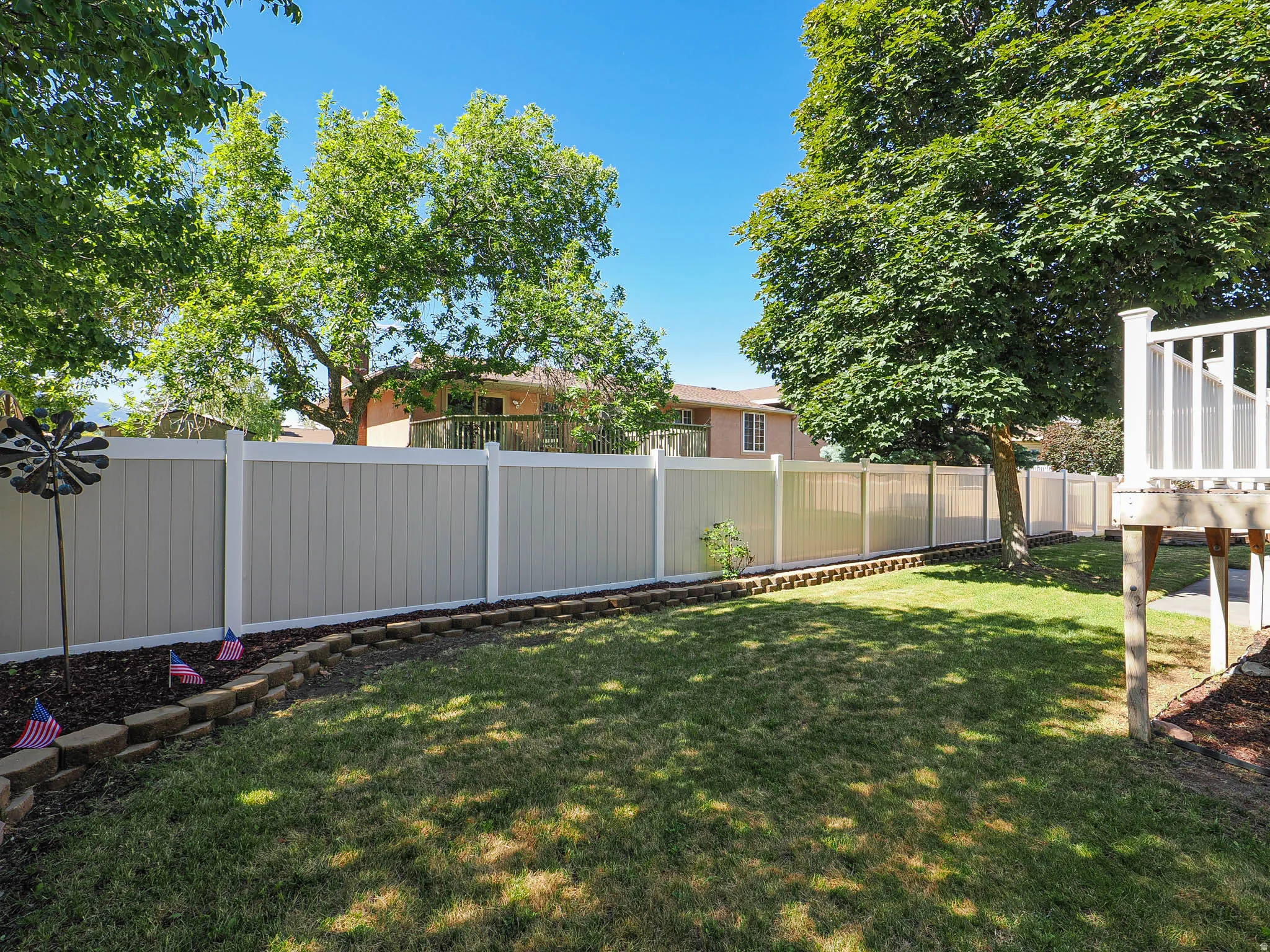 Expansive backyard with a manicured lawn, full-height privacy fencing, and mature trees providing natural shading