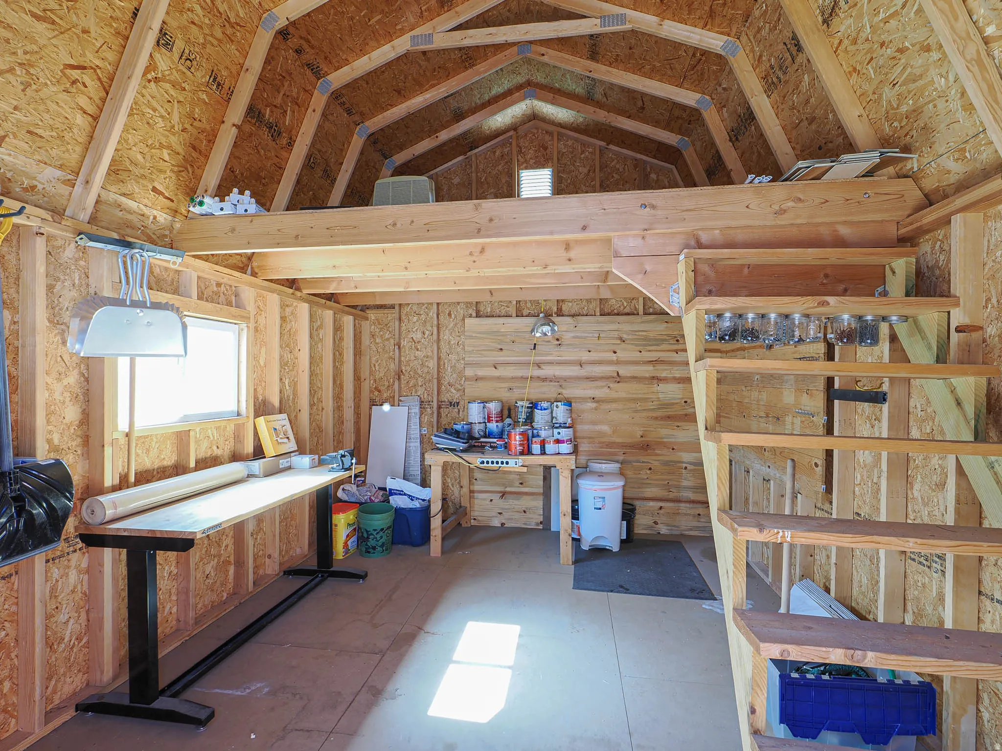 Interior structure featuring exposed wood framing, a gabled roofline, and a functional mezzanine level