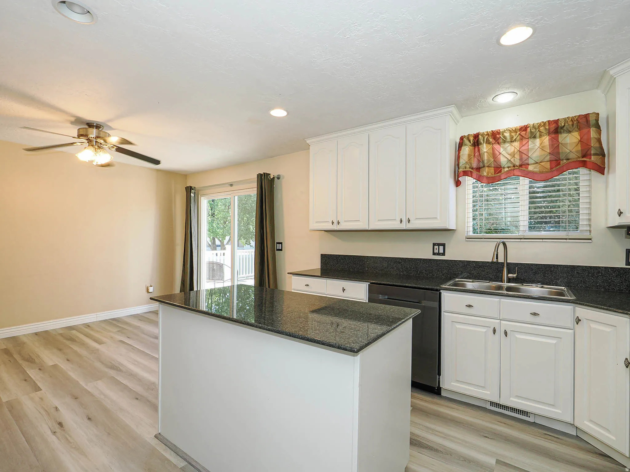Kitchen featuring white cabinetry, dark countertops, and a central island