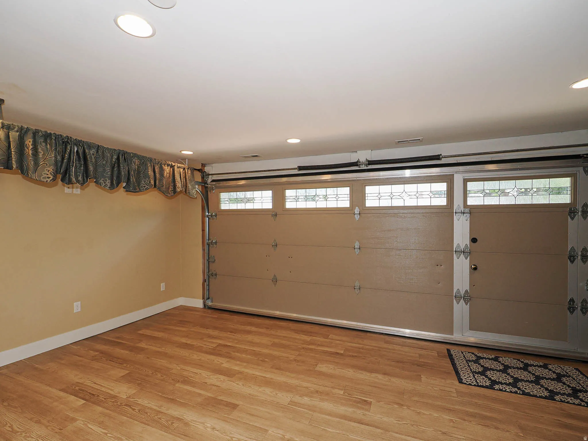 Finished space featuring wood-finish flooring, recessed lighting, and a garage door with decorative glass inserts