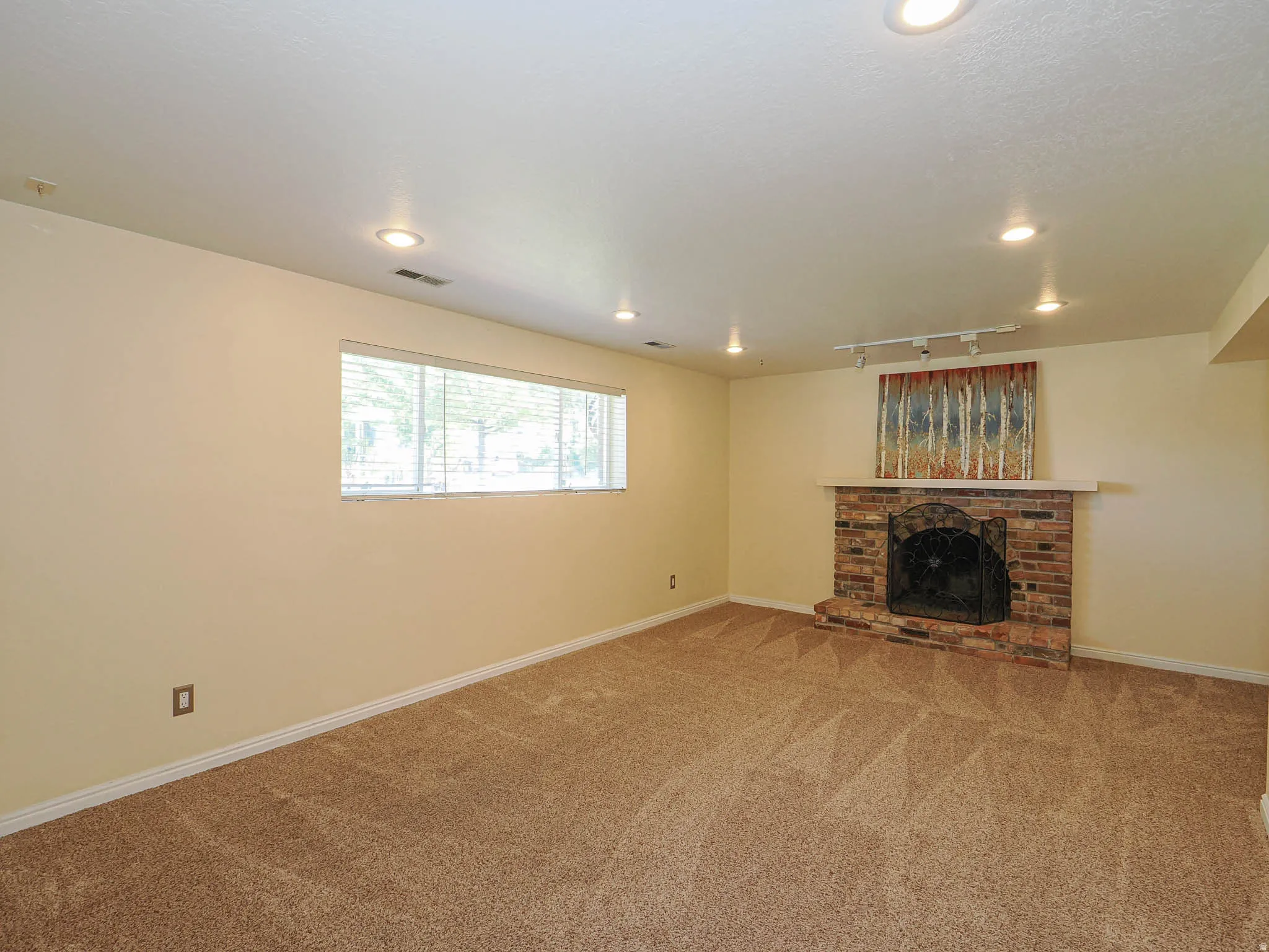 Carpeted room featuring a brick fireplace with a stone mantel, recessed lighting, and a window with horizontal blinds