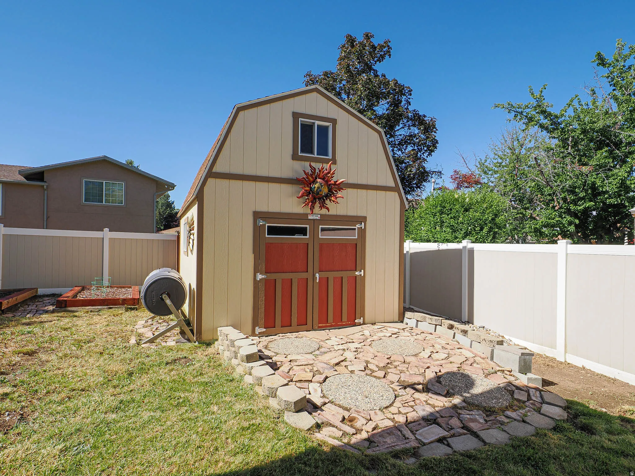 Backyard storage shed featuring a gambrel roof and red double doors