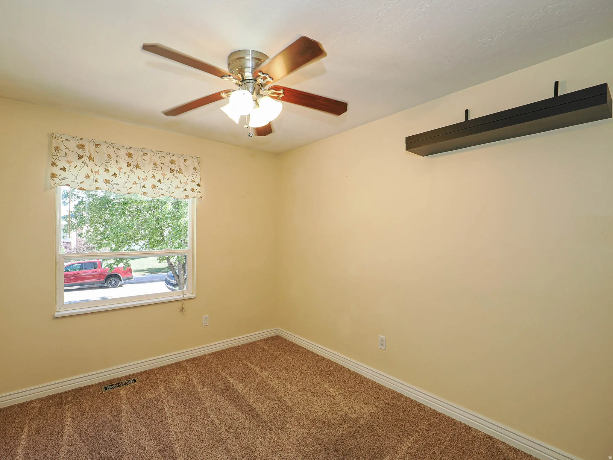 Carpeted room with a ceiling fan light fixture