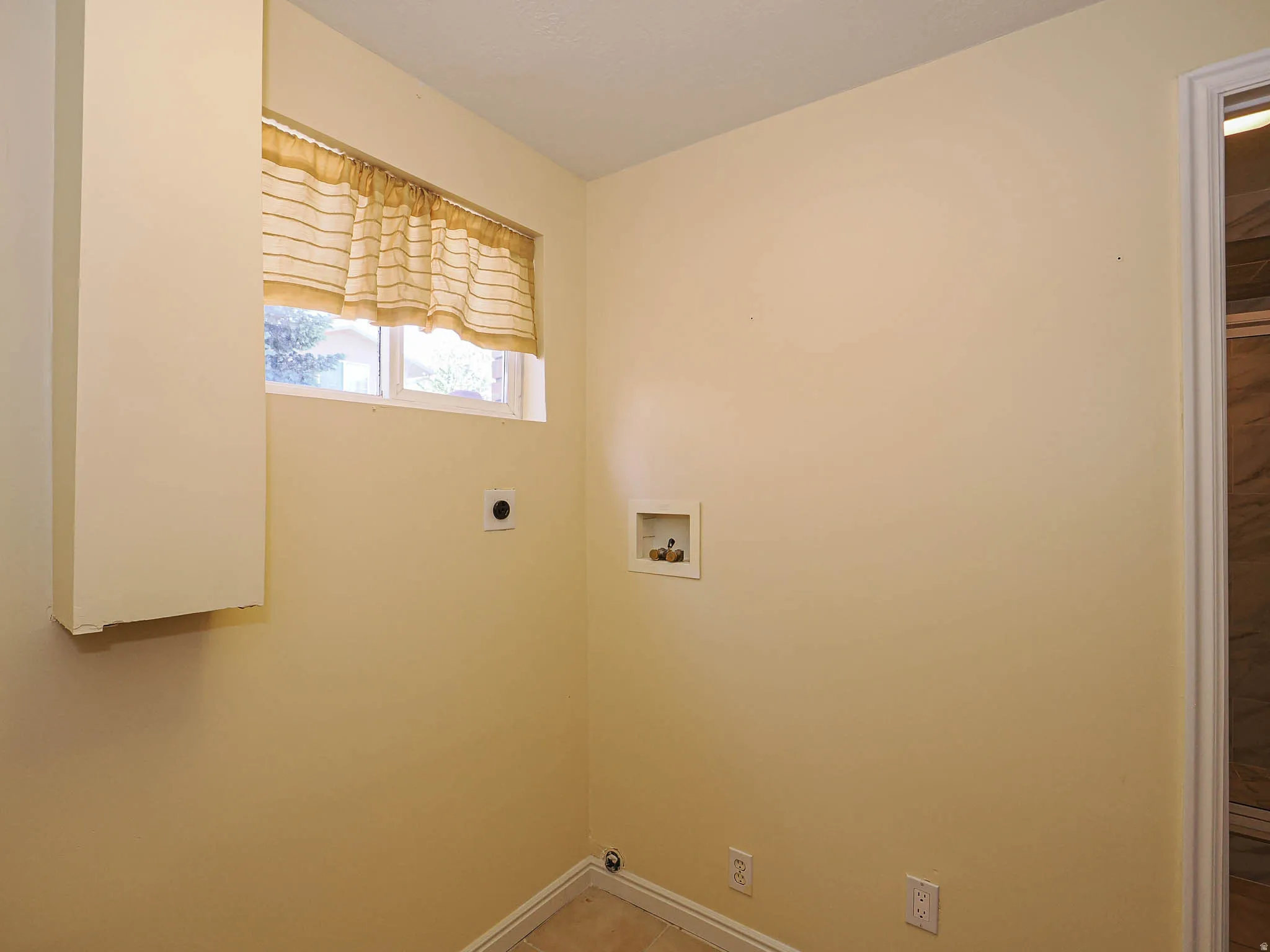 Utility room featuring a window, built-in wall cabinet, and tile flooring