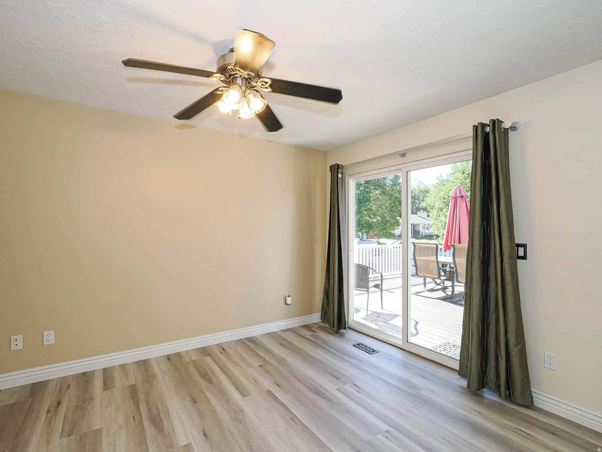 Spacious room featuring wood-finish flooring and a ceiling fan with integrated lighting