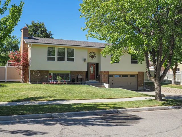 Split-level residence featuring a stucco and brick facade, an attached two-car garage, and a central entryway