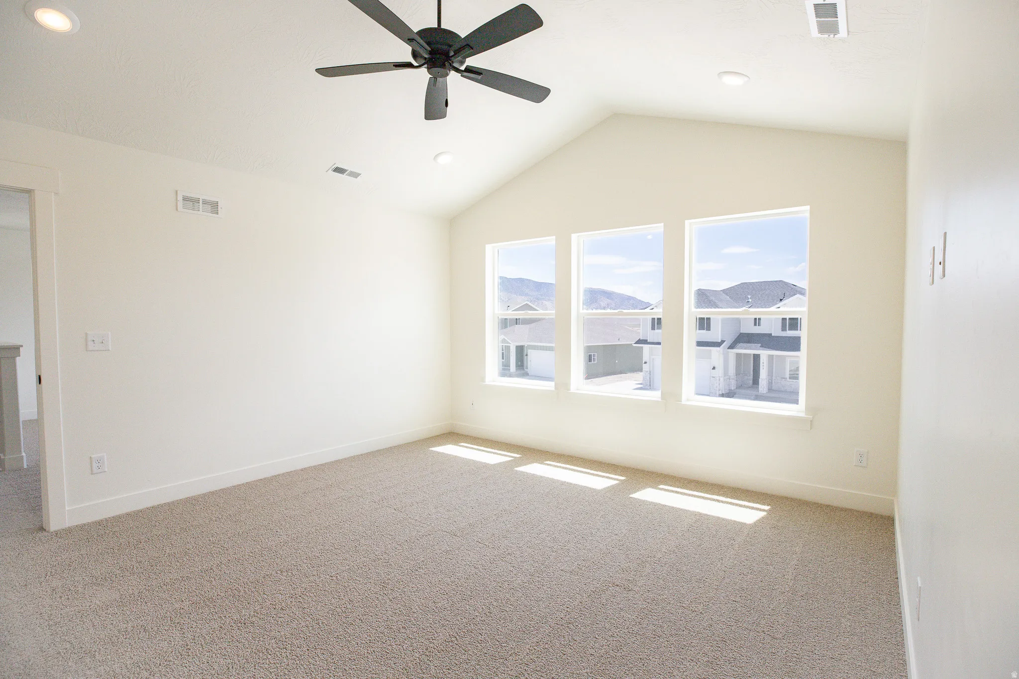 Large primary bedroom with vaulted ceiling and ceiling fan.