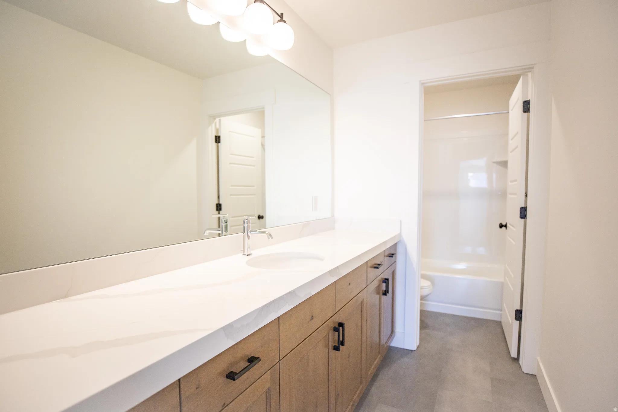 Terrific secondary bath with stained wood cabinets, quartz slab countertops, extra-long vanity and separate room for the shower.