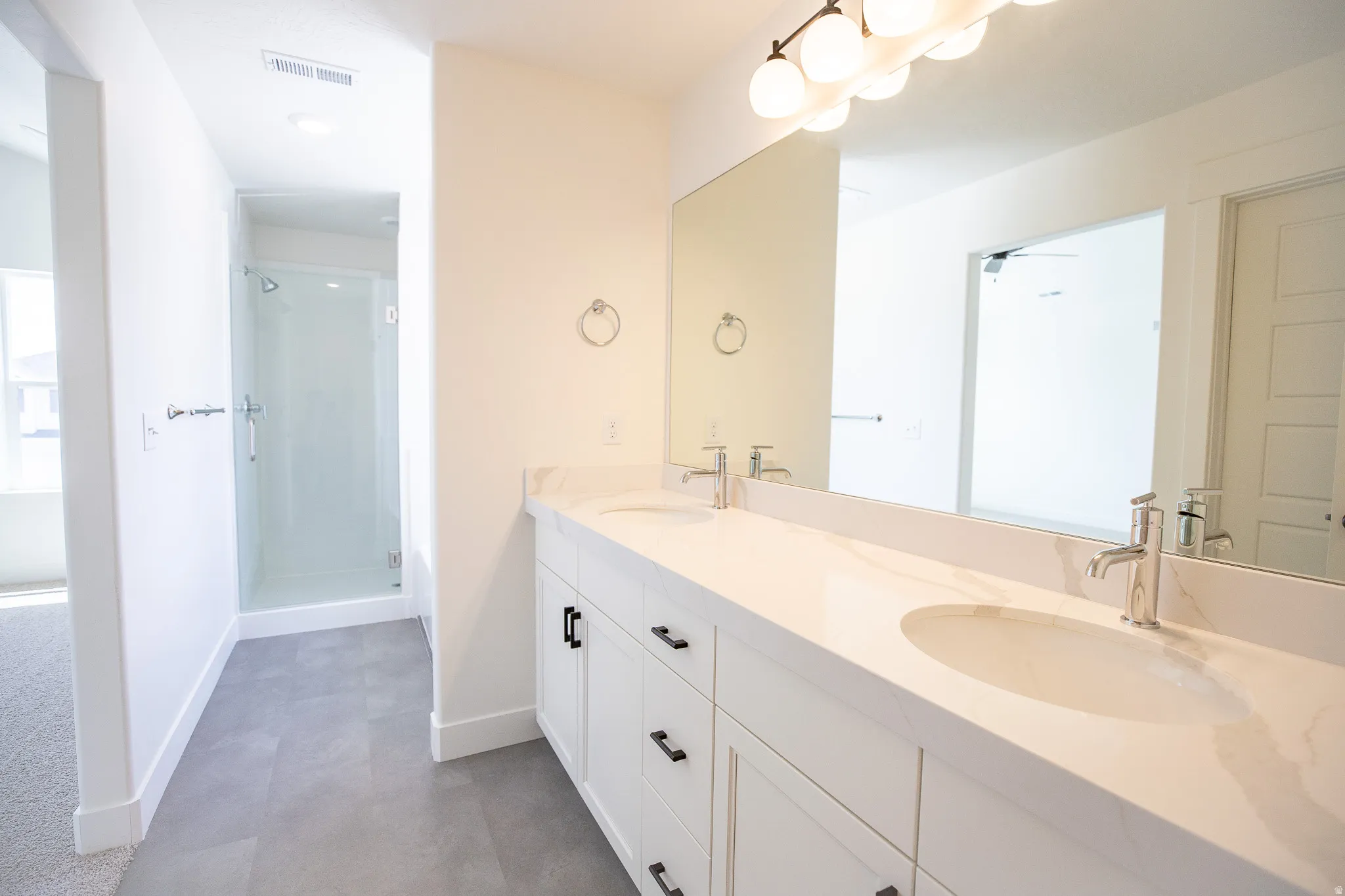 Primary bathroom with stained wood cabinets, dual sinks and quartz slab countertops, soaker tub and large shower with two shower heads.