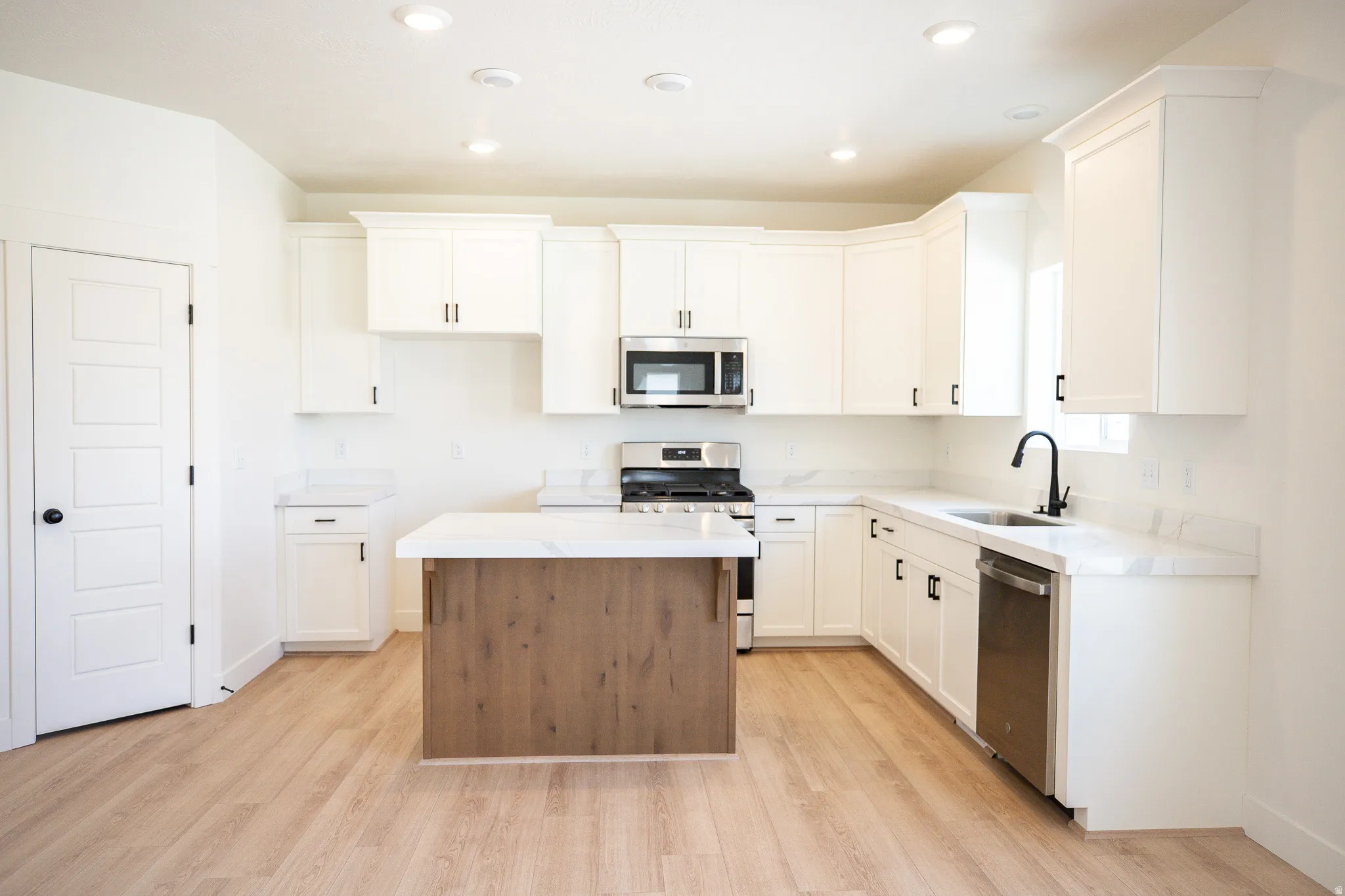 Terrific kitchen with painted wood cabinets, ceiling height uppers, quartz slab countertops, stained wood island, gas range, microwave, dishwasher and disposal with adjacent dining area.