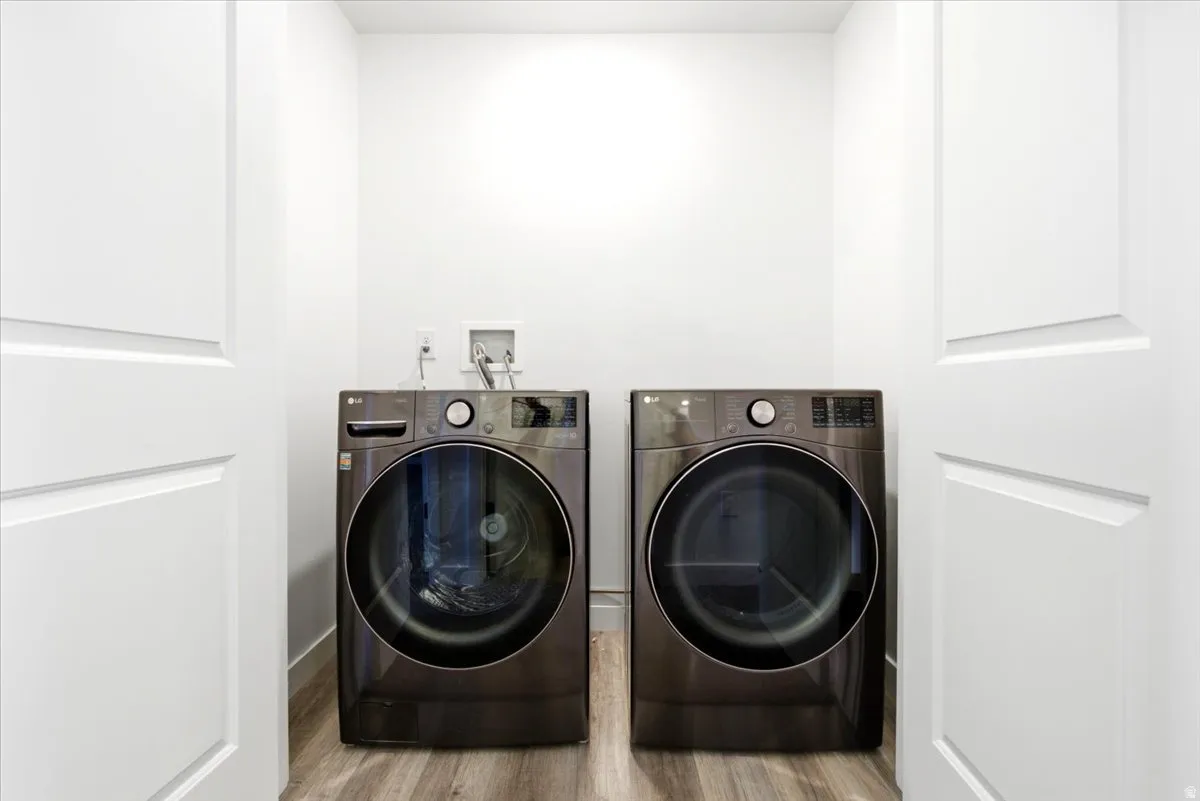 Dedicated laundry area featuring a front-loading washer and dryer, wood-finish flooring, and white paneled doors