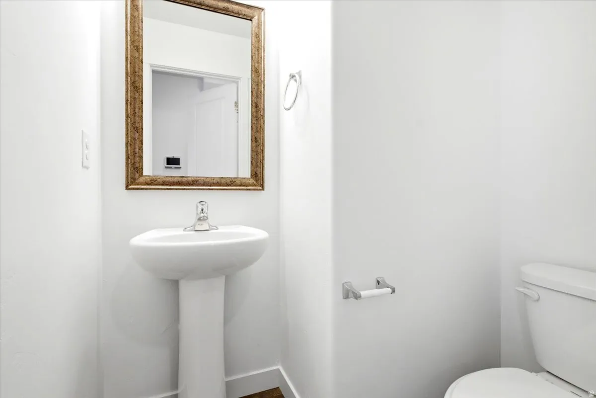 Pedestal sink with a polished chrome faucet and a framed mirror
