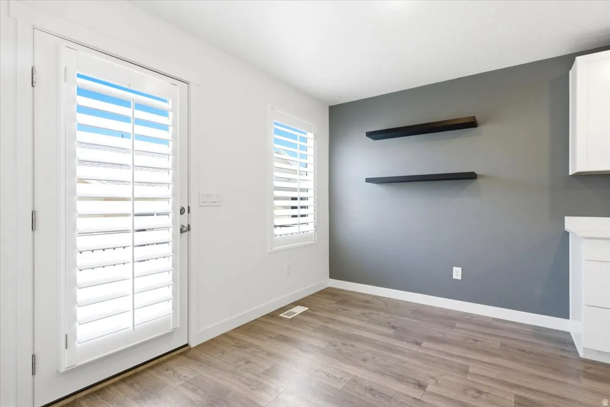 Interior space featuring wood-finish flooring, white baseboards, and a contrasting accent wall