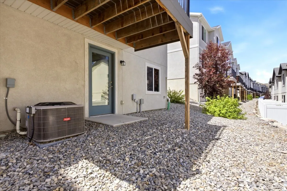 Lower-level exterior featuring a glass-paneled door, concrete patio, and a gravel ground cover