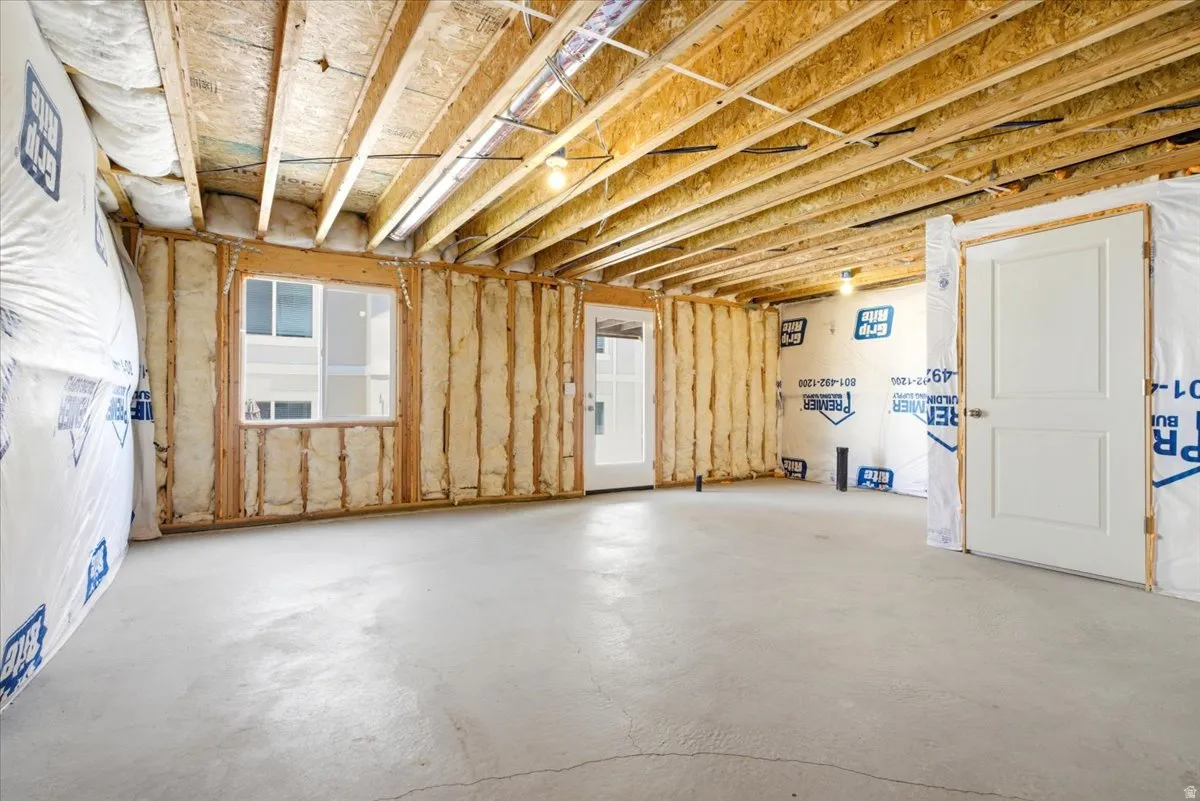 Unfinished basement space featuring exposed wood joists and concrete flooring