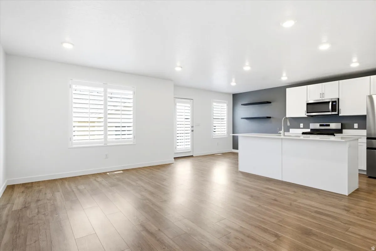 Open-concept living space featuring wood-finish flooring, recessed lighting, and white plantation shutters