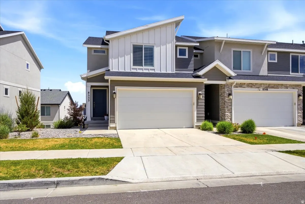 Modern townhome exterior featuring an attached two-car garage, concrete driveway, and front entryway