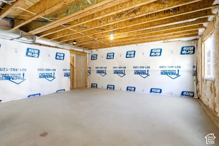Unfinished basement featuring exposed wood joists, a poured concrete floor, and insulated walls