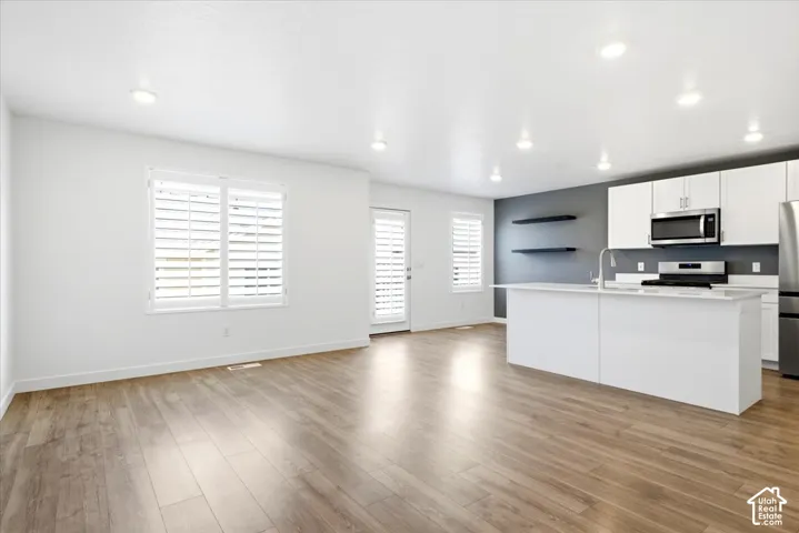 Open-concept living space featuring wood-finish flooring, recessed lighting, and white plantation shutters