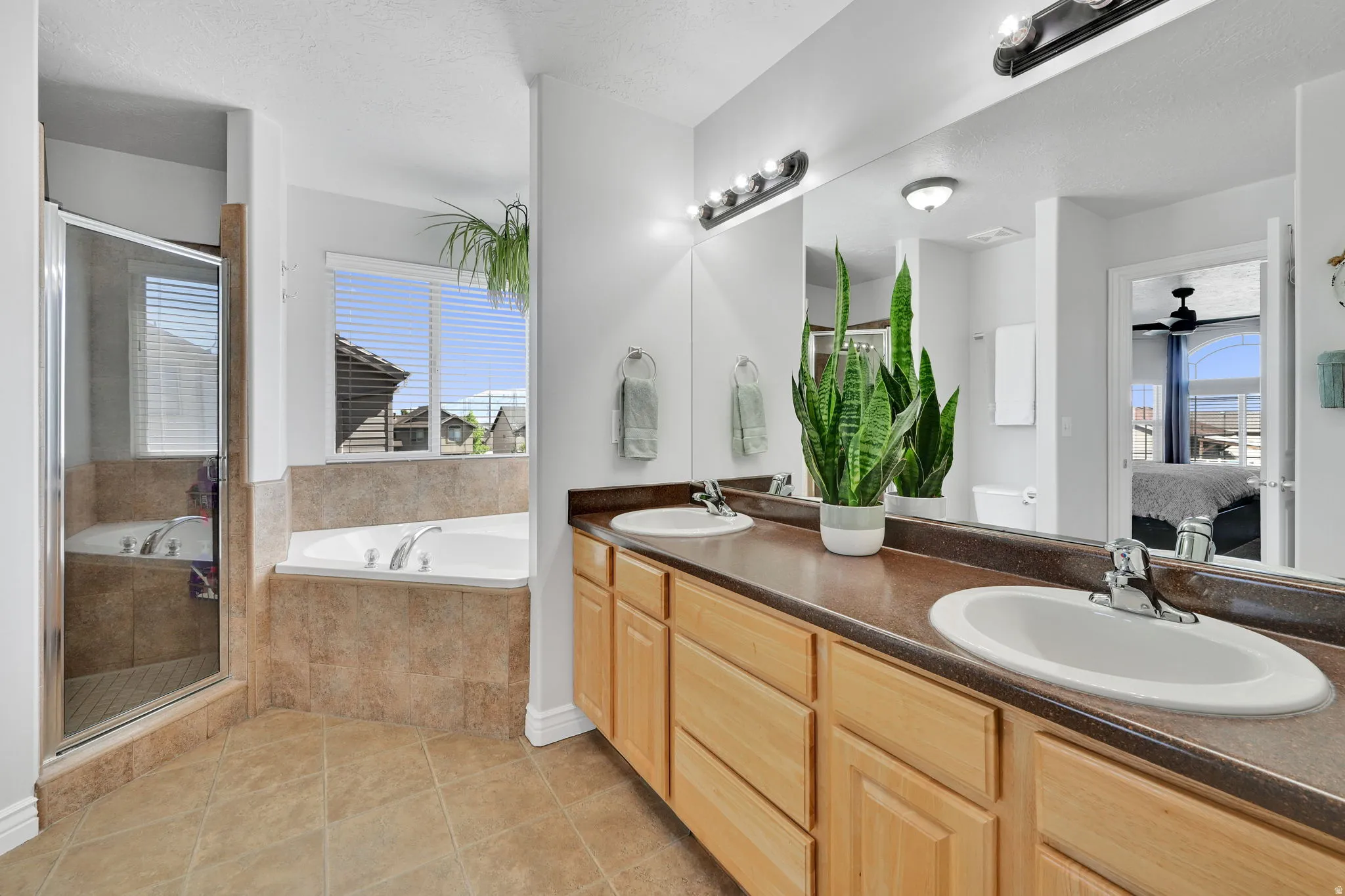 Bathroom featuring a double vanity with light wood cabinetry, dual undermount sinks, and a dark countertop