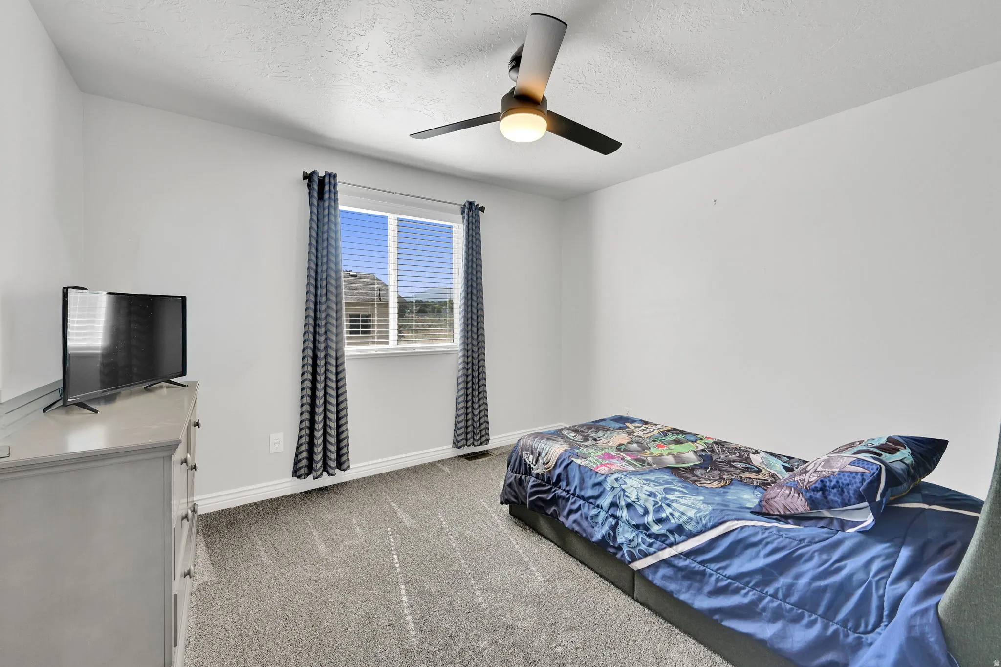 Room featuring light gray walls, gray carpet flooring, and a ceiling fan with integrated lighting