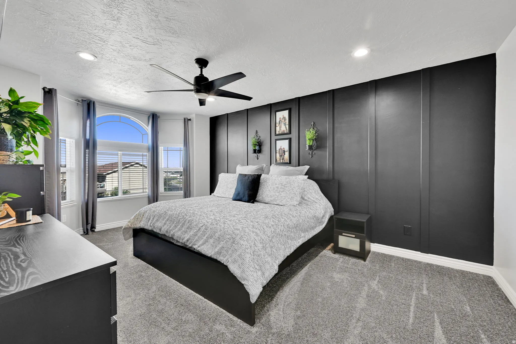 Bedroom featuring a striking accent wall with vertical paneling, a ceiling fan with integrated lighting, and recessed ceiling lights