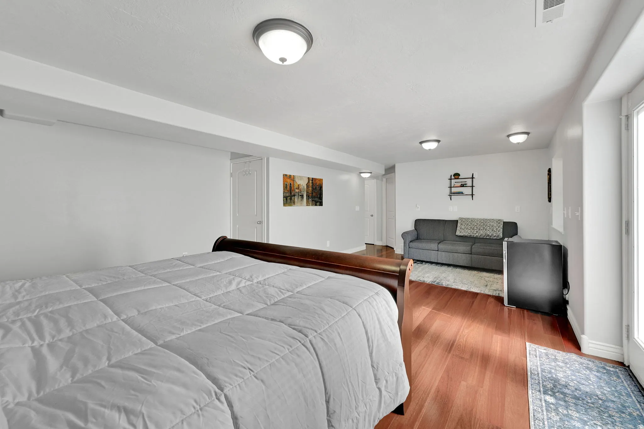 Spacious room featuring wood-finish flooring, white walls, and multiple flush-mount ceiling lights