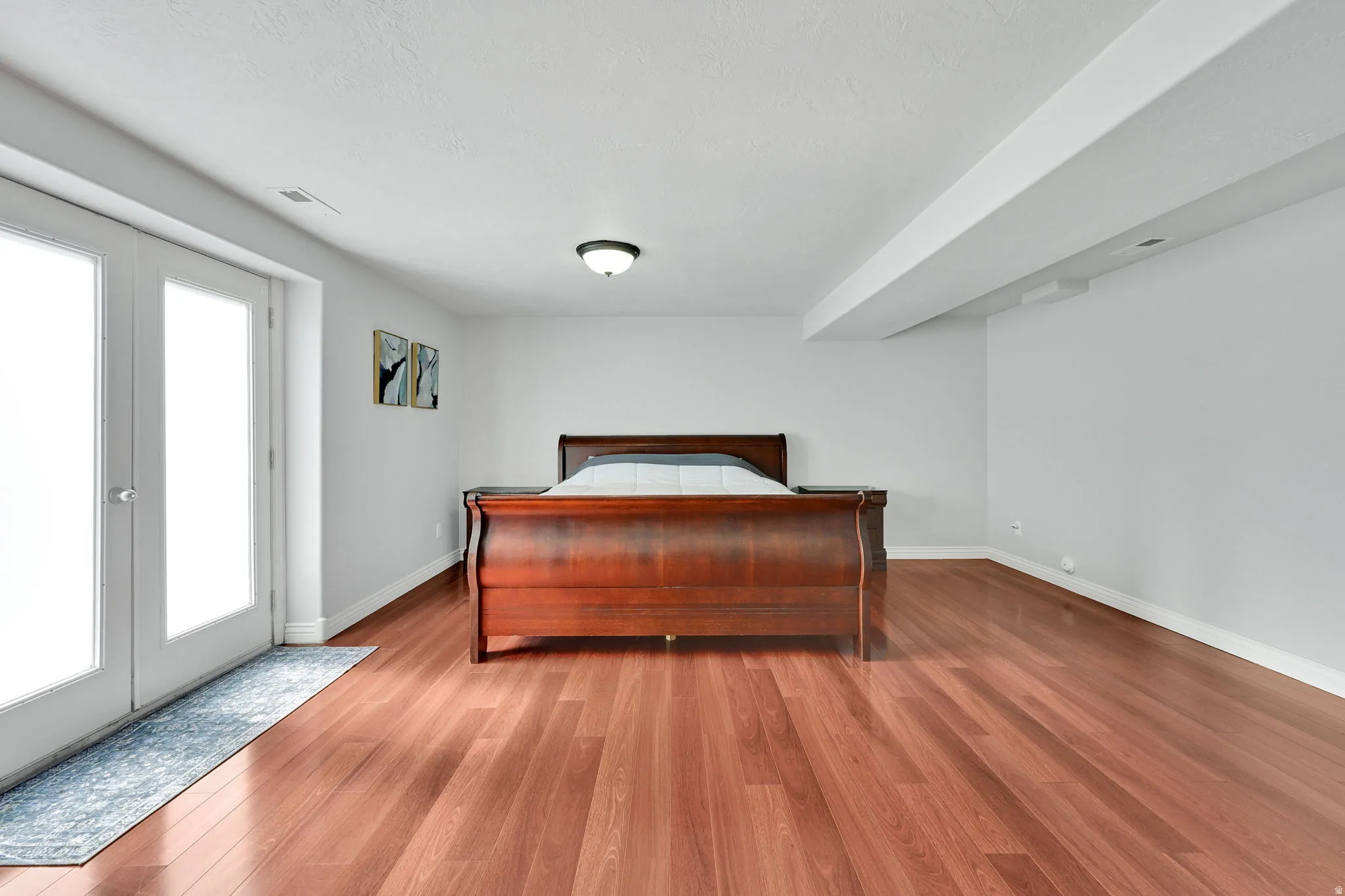 Room featuring wood-finish flooring, white walls, and a ceiling-mounted light fixture