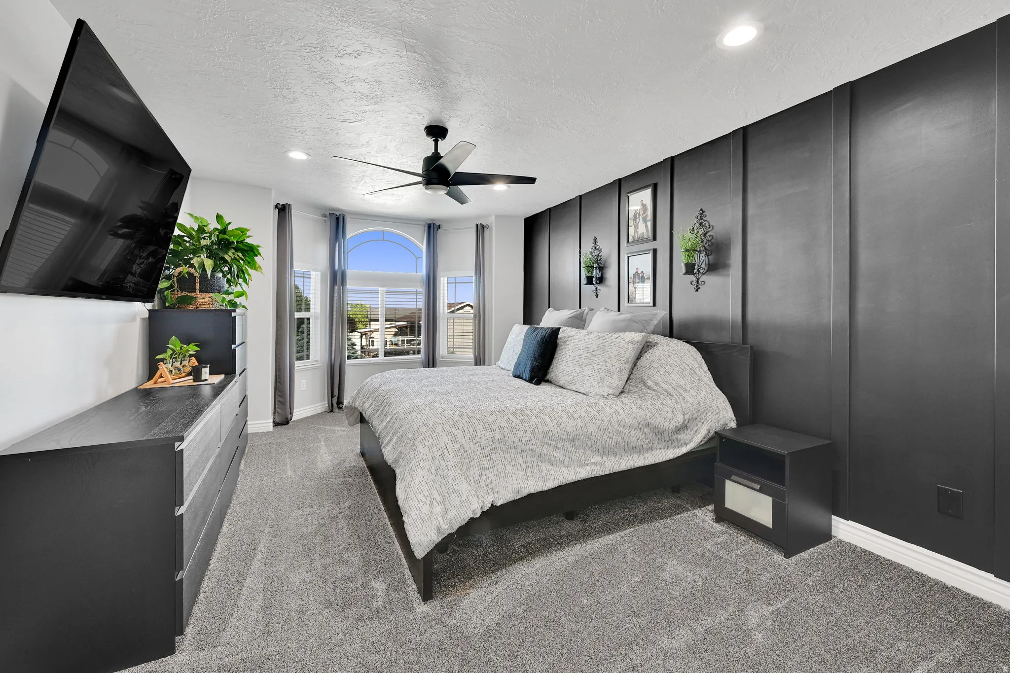 Spacious room featuring a bay window with arched transom, textured carpeting, recessed lighting, and a ceiling fan