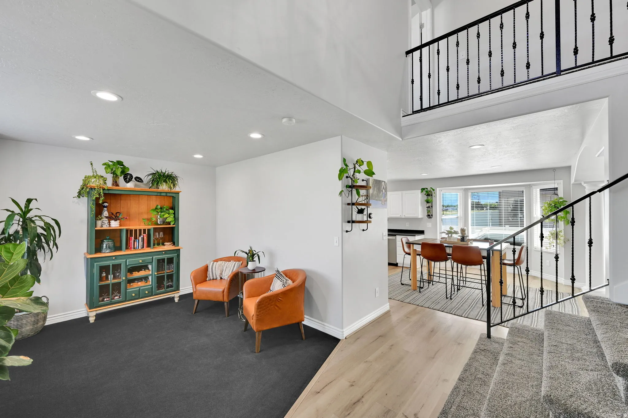 Multi-level interior featuring a carpeted living area with recessed lighting, wood-finish flooring, and a kitchen visible through an archway