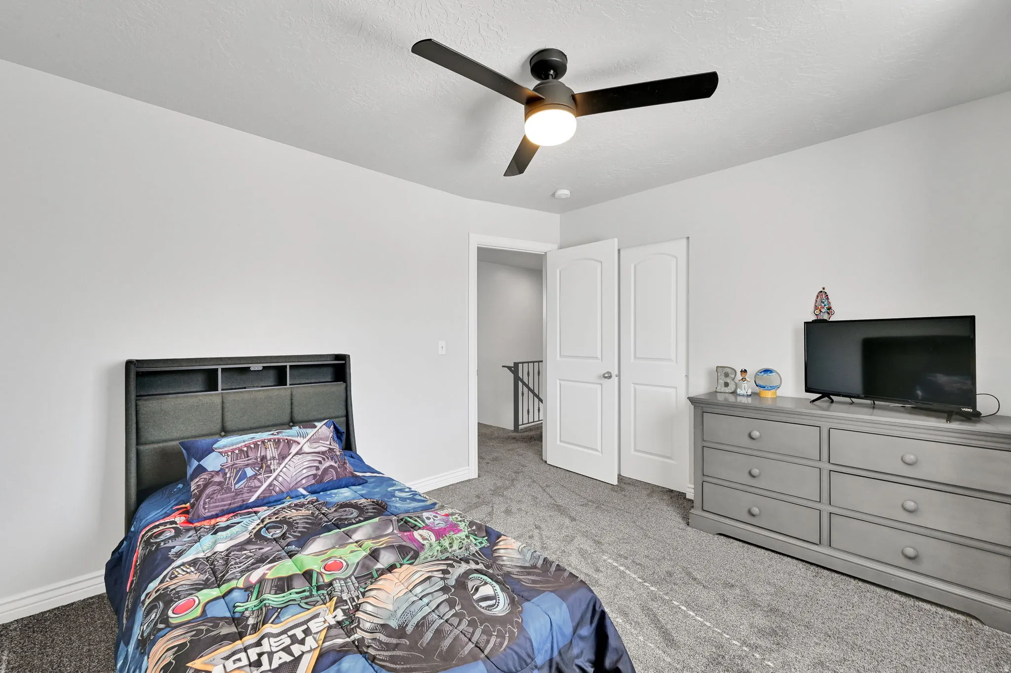 Carpeted room featuring a ceiling fan with integrated lighting, white walls, and white trim
