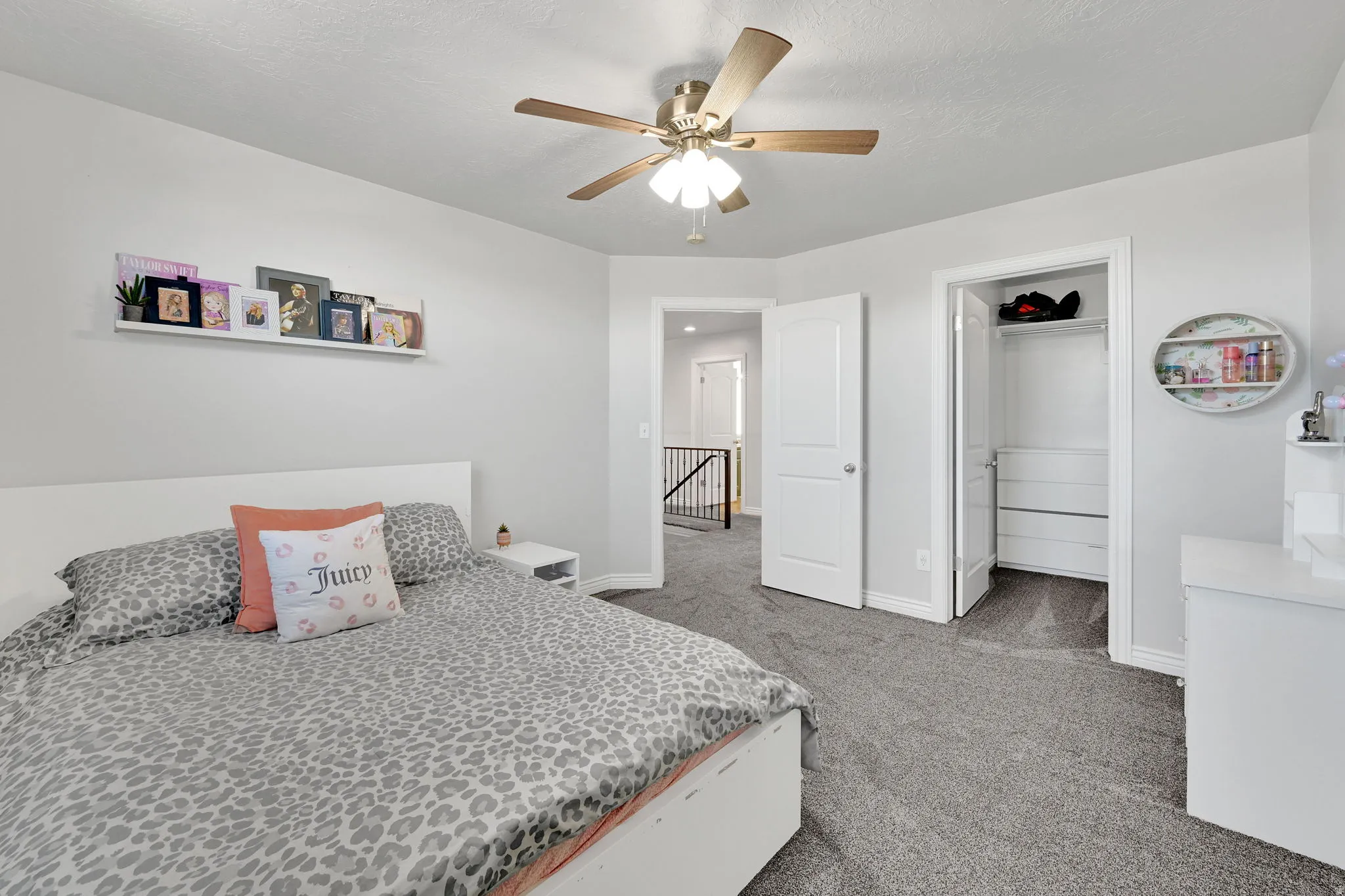 Carpeted room featuring a ceiling fan with light fixture, built-in closet storage, and white trim