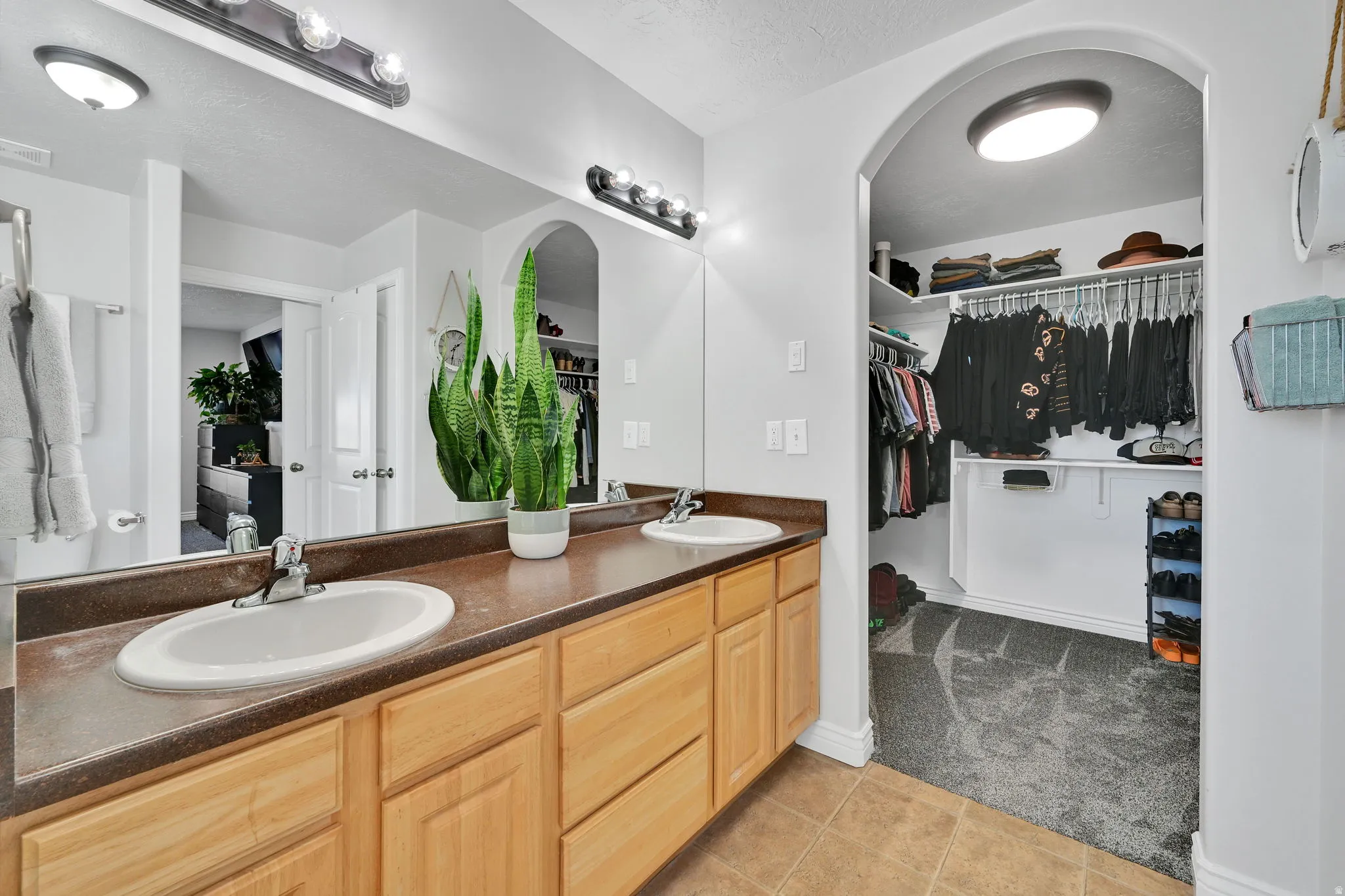 Double vanity with light wood cabinetry, brown countertops, and dual oval sinks