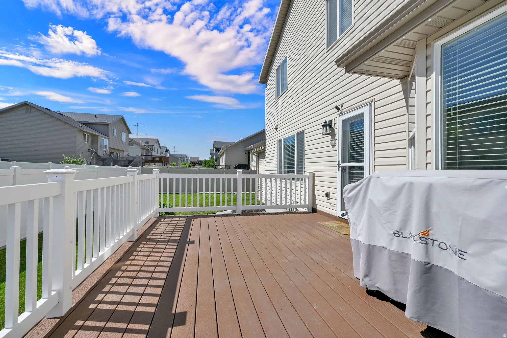 Spacious wood-finish composite deck with white railing, overlooking a fenced yard
