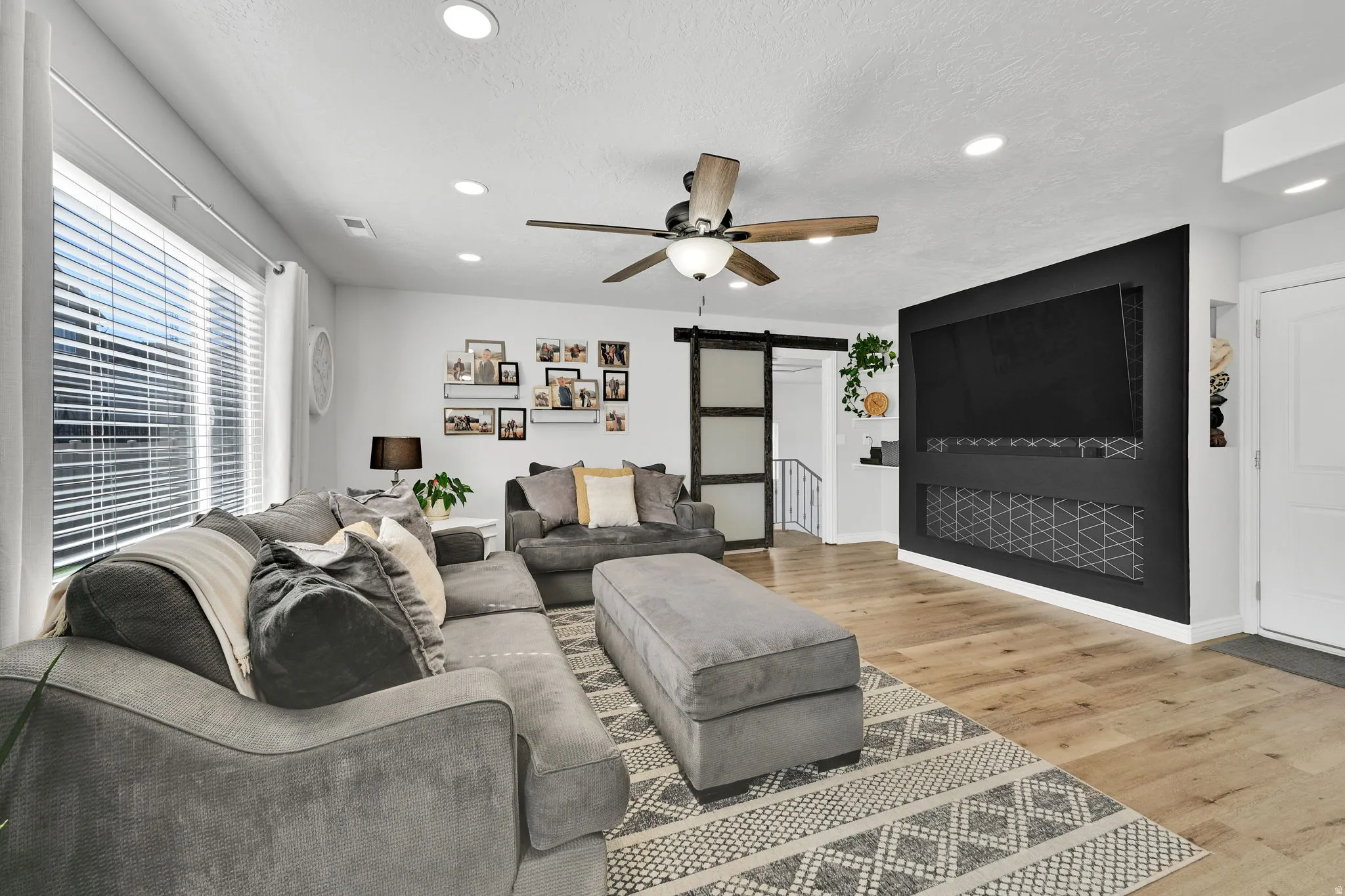 Spacious living area featuring light wood-finish flooring and a contemporary ceiling fan