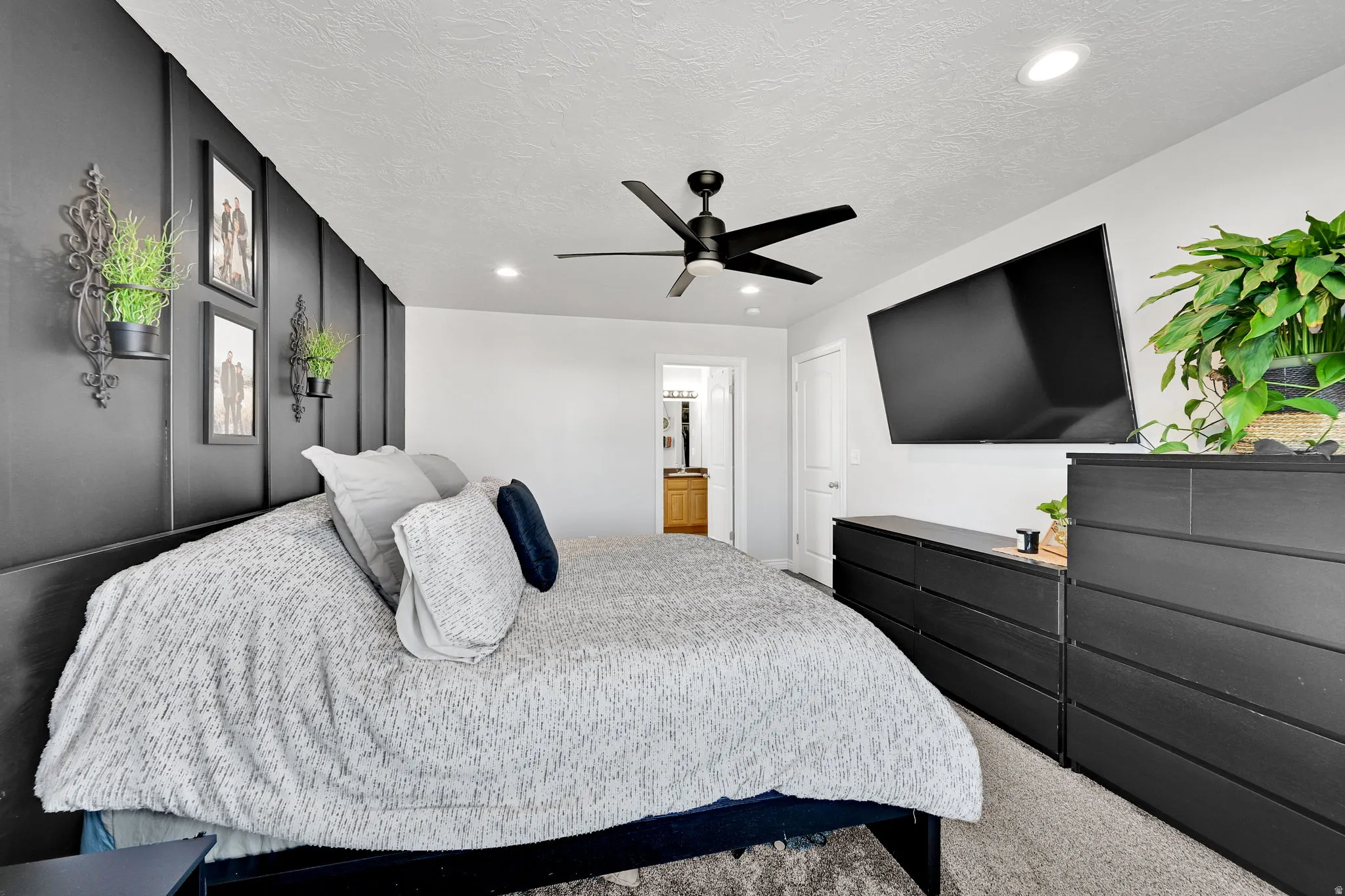 Bedroom featuring a dark accent wall with vertical paneling, recessed lighting, and a black ceiling fan