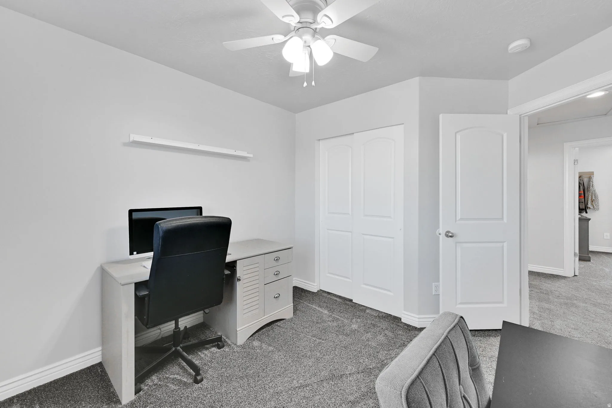 Carpeted room featuring a ceiling fan, light gray walls, white baseboards, and a built-in closet with double sliding doors