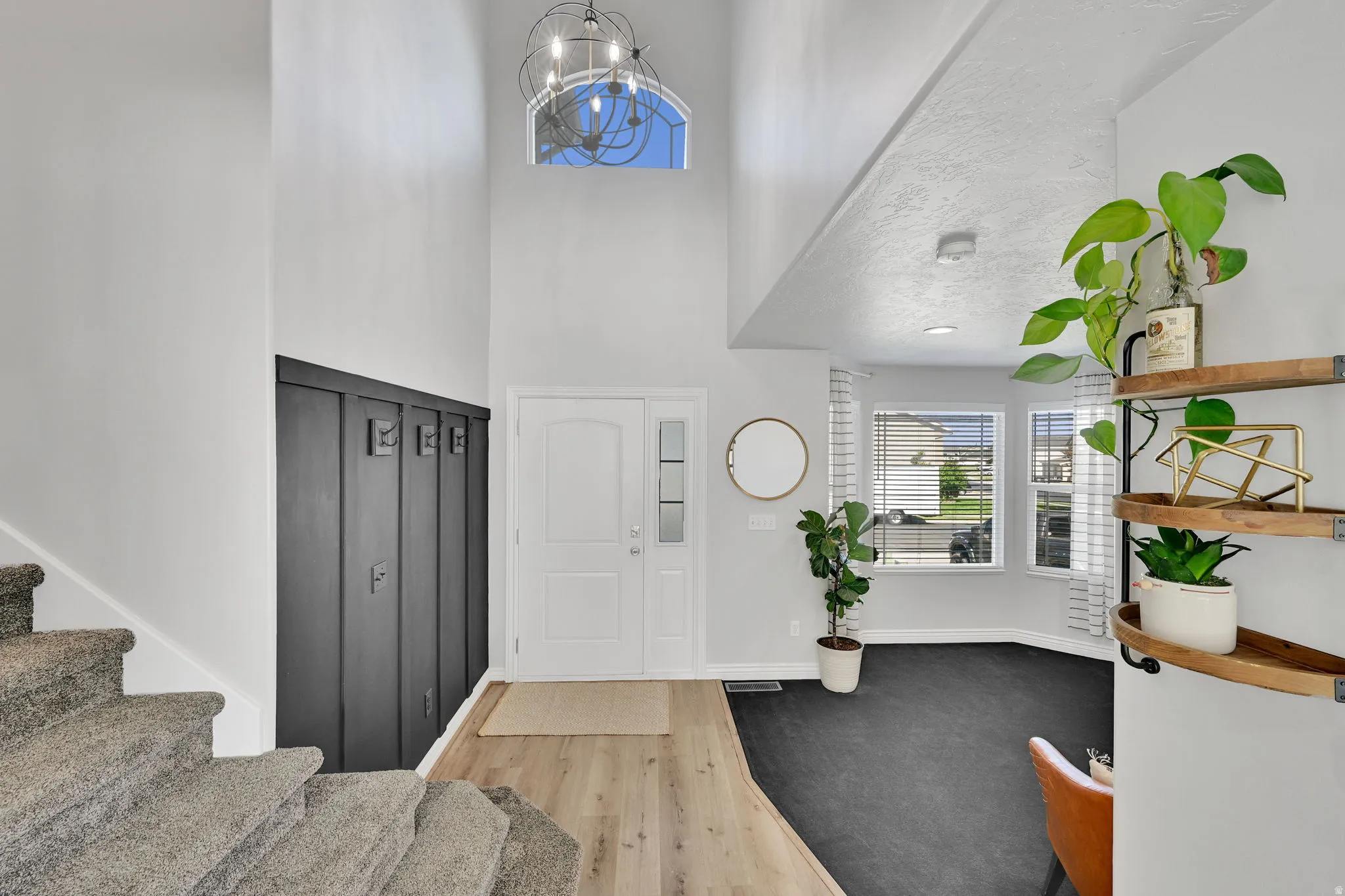 Two-story entryway featuring a neutral color palette, wood-finish flooring, and a contemporary chandelier