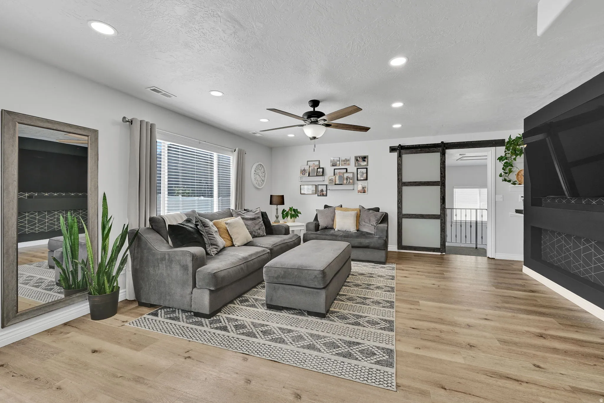 Open-concept living area featuring wood-finish flooring, recessed lighting, and a ceiling fan