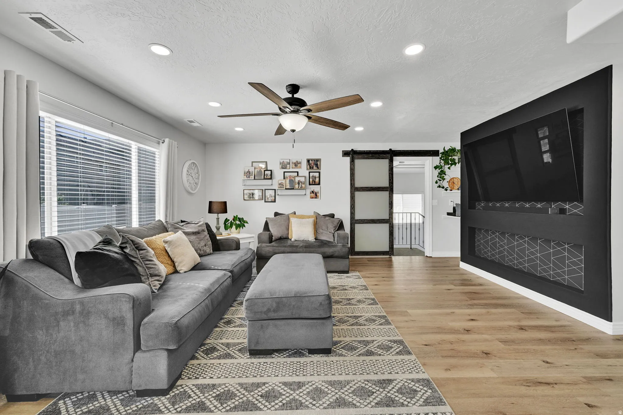 Spacious living area featuring light wood-finish flooring and a built-in entertainment center with geometric detailing