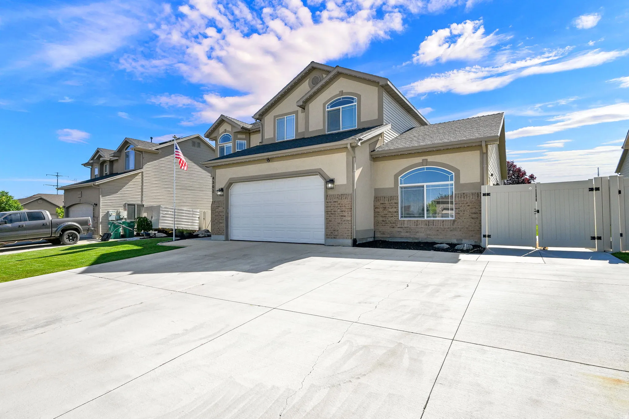 Two-story residence featuring a two-car garage, arched window accents, and a light-colored stucco and brick facade