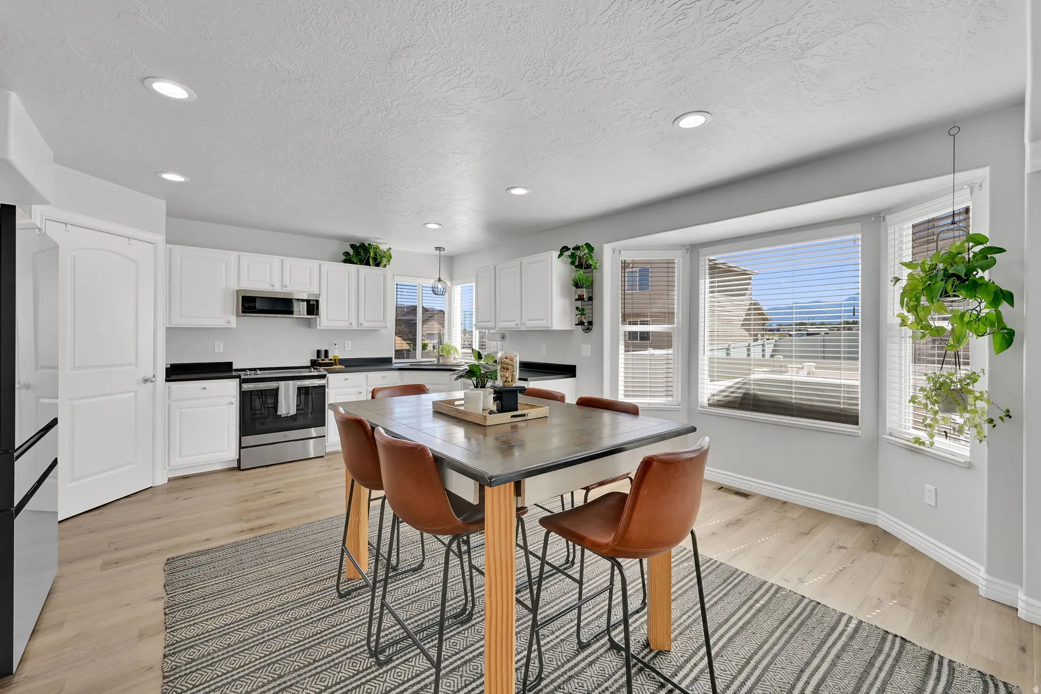 Bright kitchen featuring white cabinetry, dark countertops, and stainless steel appliances