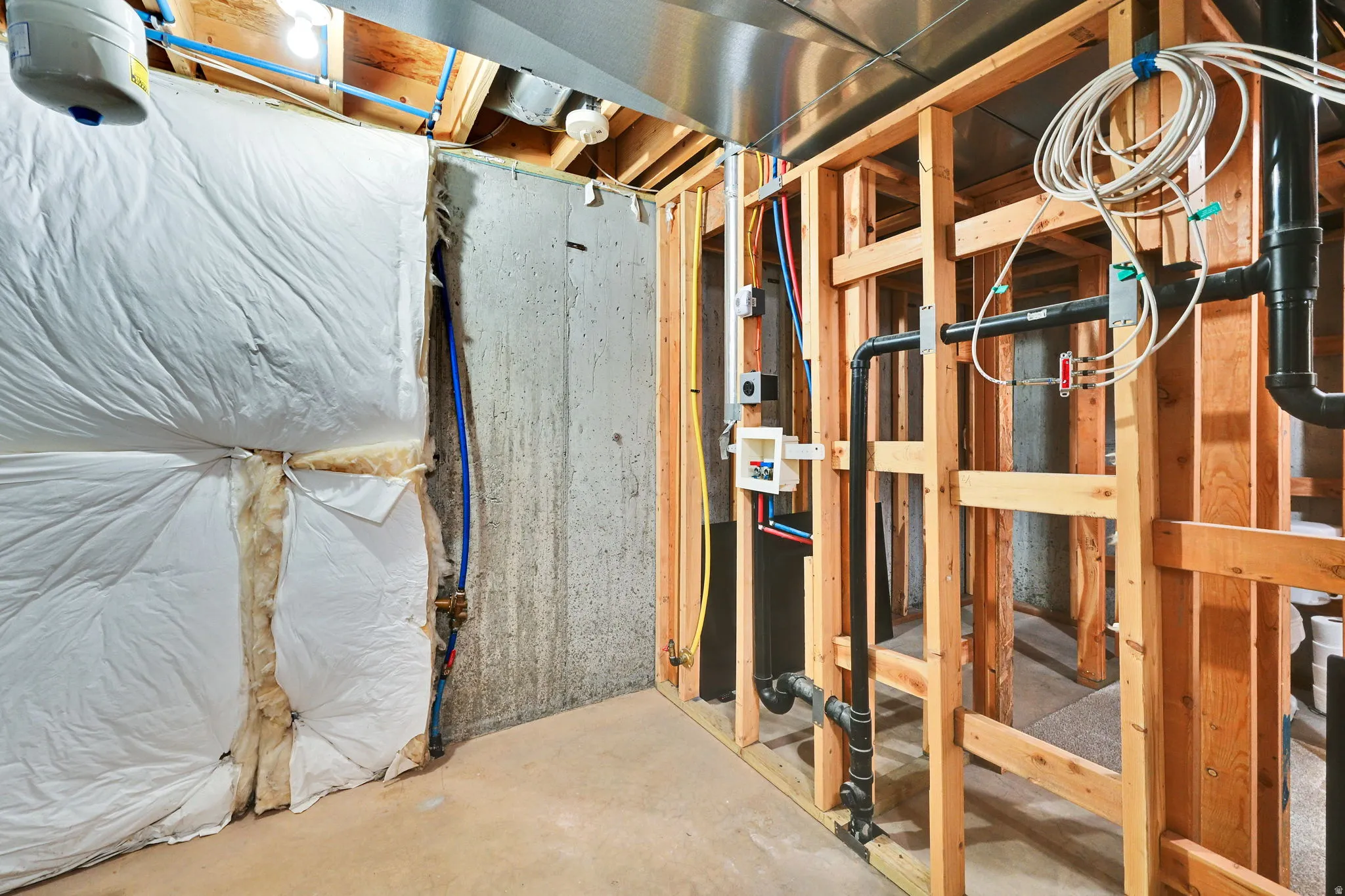 Unfinished basement area featuring concrete foundation walls and exposed wood framing
