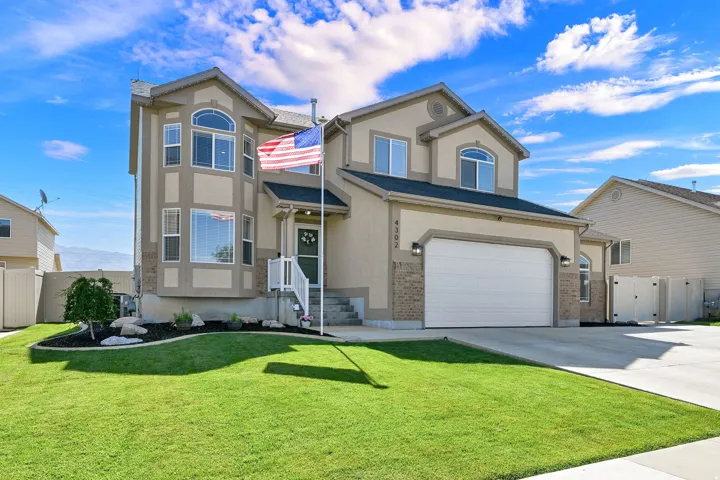 Two-story residence featuring a bay window, a dual-door garage, and a manicured lawn