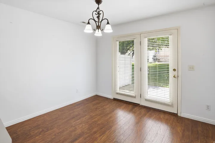 Wood-finish flooring throughout, featuring a double French door entry with integrated blinds