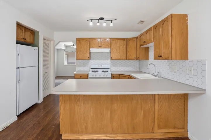 Kitchen featuring wood-finish cabinetry, white countertops, and hexagonal tile backsplash