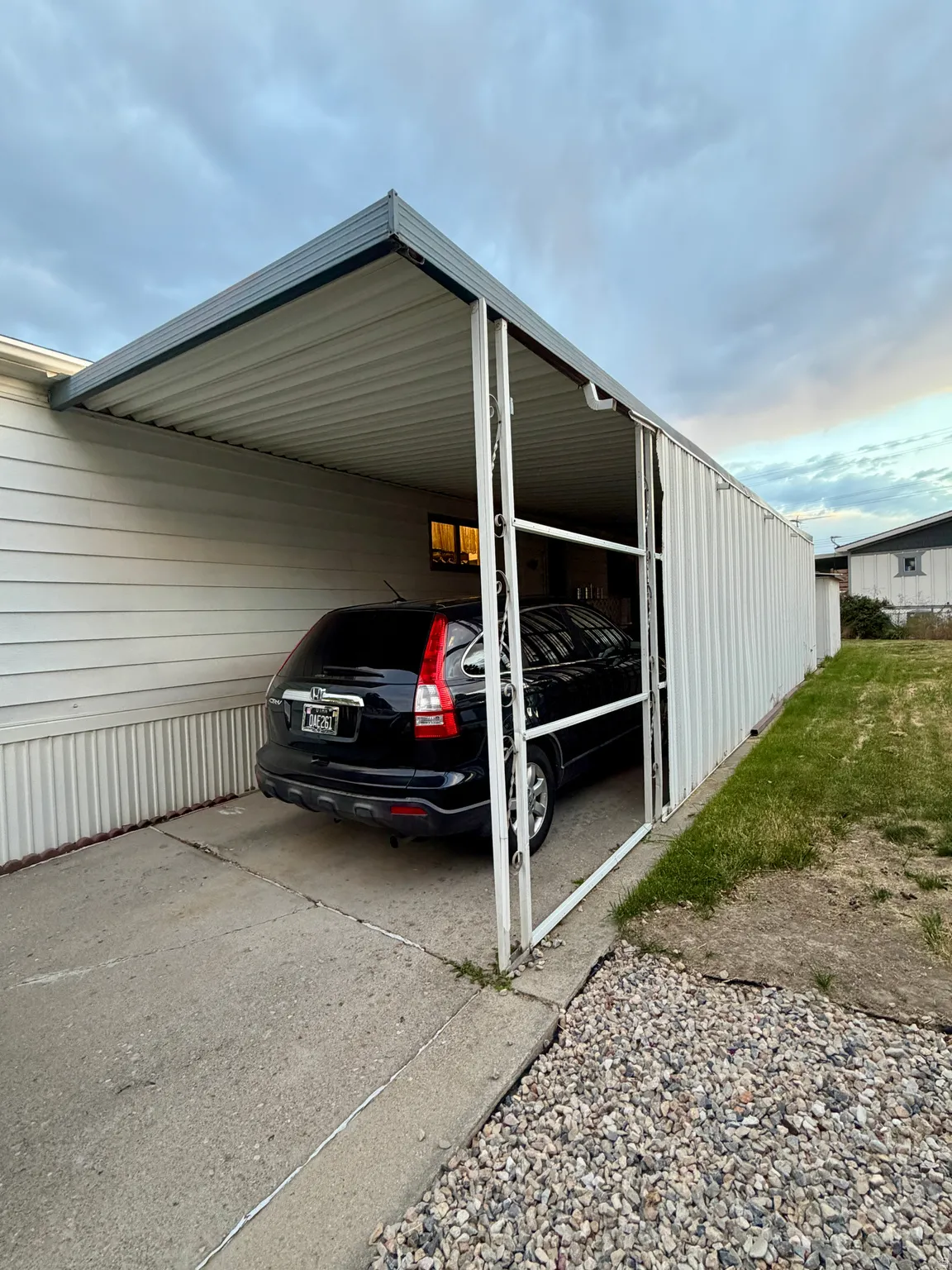 Attached carport with a concrete driveway and corrugated metal roofing