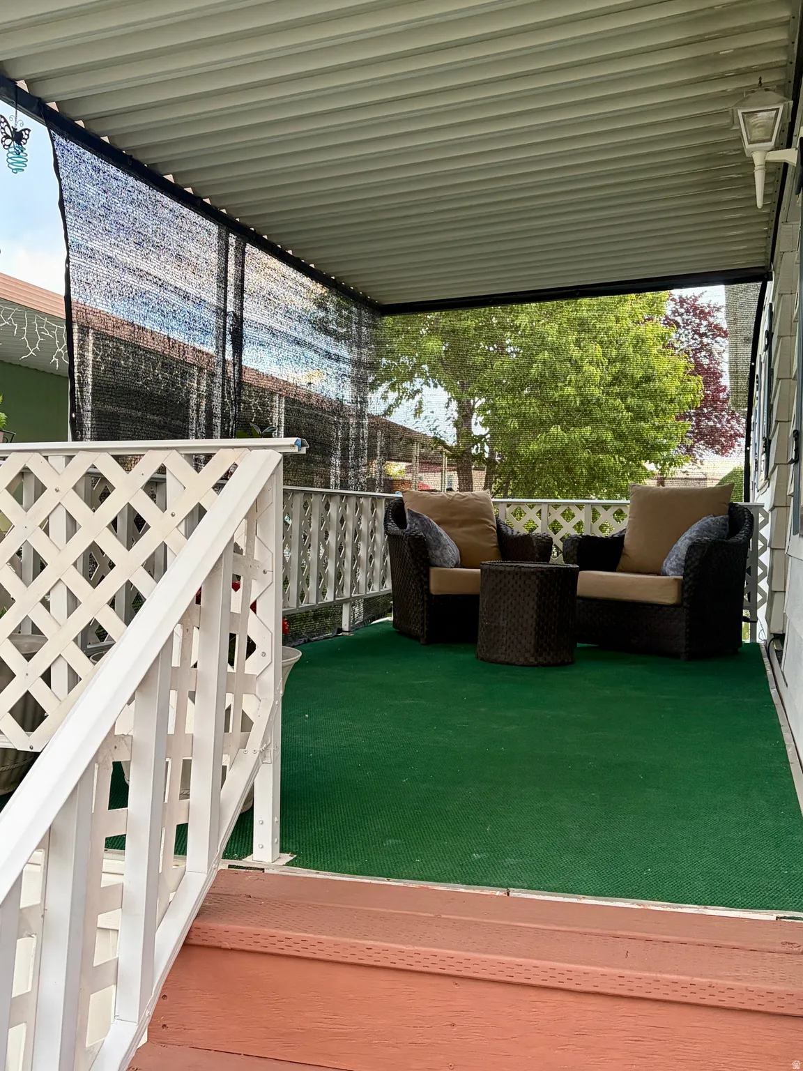 Covered cozy front porch featuring a privacy screen and white lattice railing